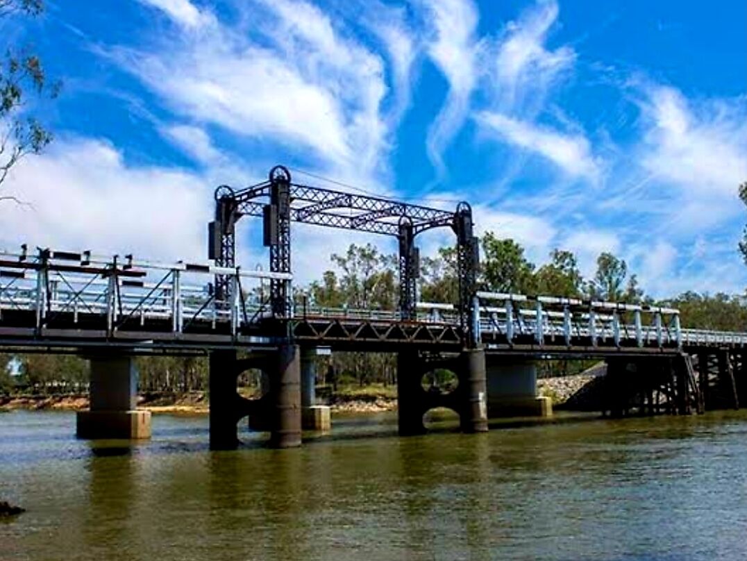 Un puente de acero con estructura de celosía cruzando un río.