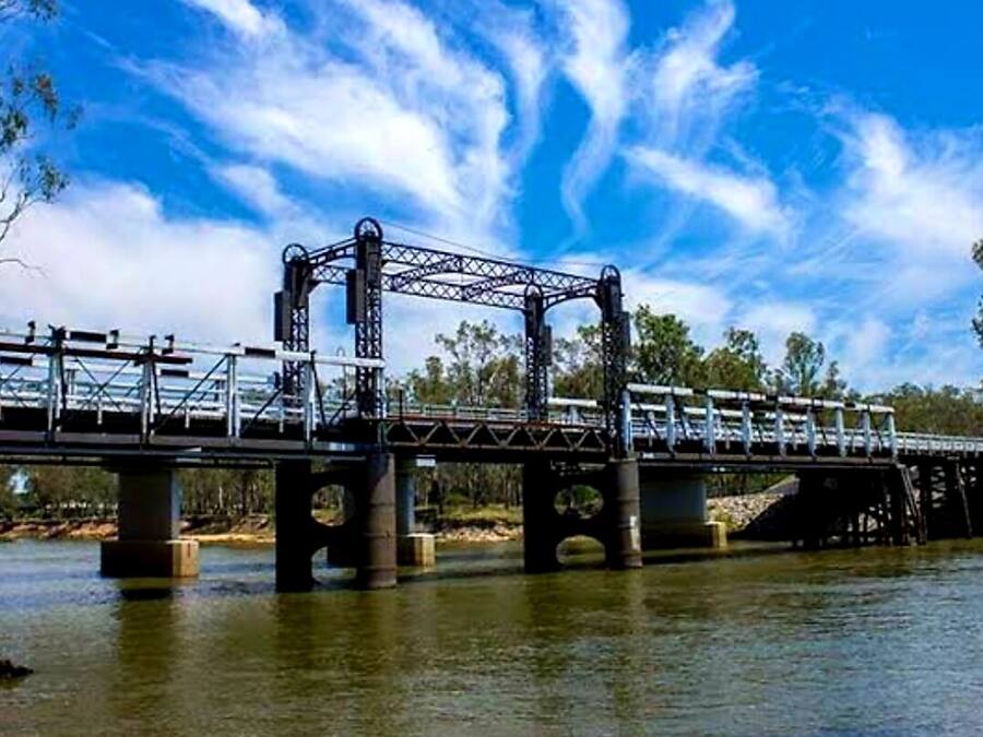 Un puente de acero con estructura de celosía cruzando un río.