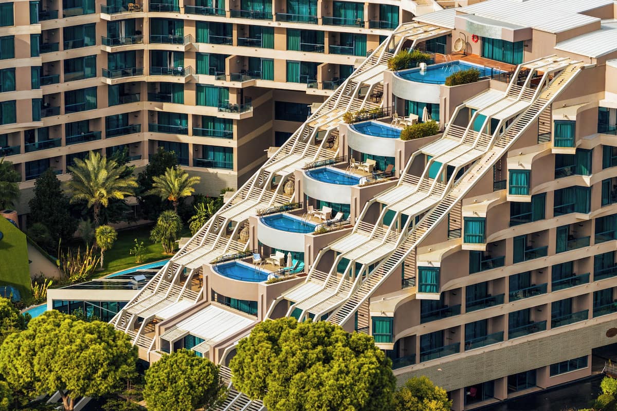 A multi-story hotel with balconies, a swimming pool, and a landscaped garden.