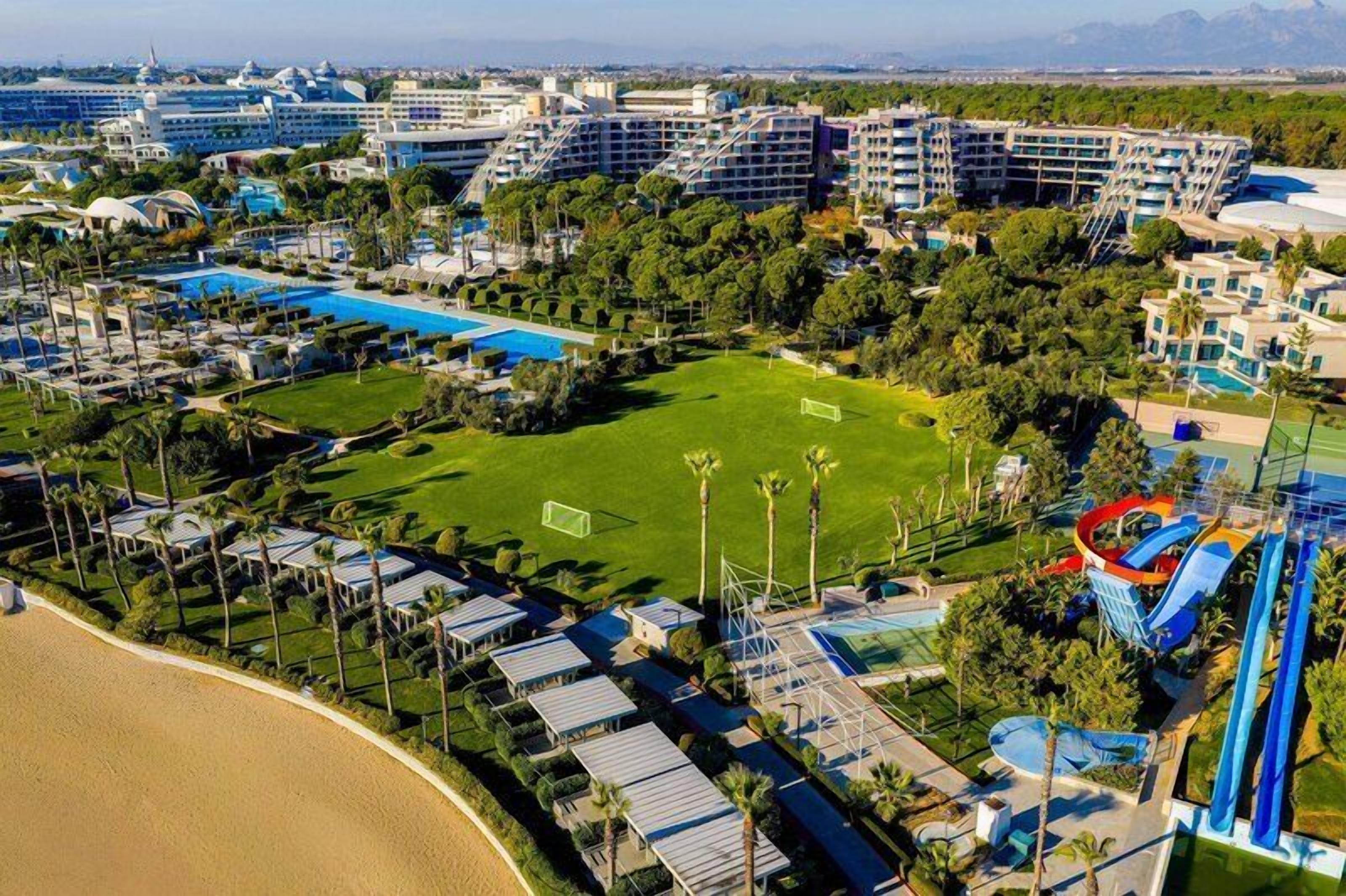 Een resort met meerdere gebouwen, een groot zwembad en een sportveld.