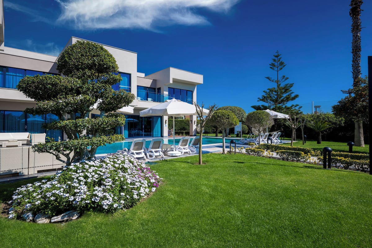 A modern building with a swimming pool, sun loungers, and well-maintained gardens.