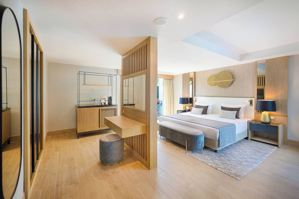 A modern bedroom with a large bed, bedside tables, a mirror, and a built-in wardrobe.