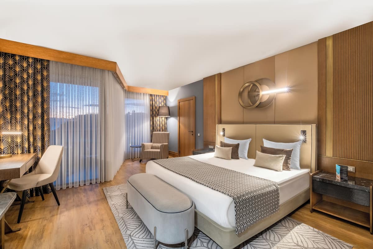 A modern hotel room with a large bed, a desk, and a seating area.