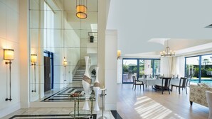 A spacious, modern interior with a dining area, a pool, and a staircase leading to upper floors. - Susesi Luxury Resort - All Inclusive (Serik)