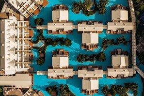 An aerial view of a resort with multiple poolside villas arranged around a central pool, surrounded by palm trees and greenery. - Susesi Luxury Resort - All Inclusive (Serik)