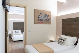 Una camera d'albergo con un letto, un comodino, una lampada e un'opera d'arte appesa al muro.
