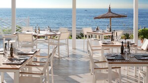 An outdoor dining area with white furniture and a view of the ocean. - Finca Cortesin Hotel Golf & Spa (Casares)
