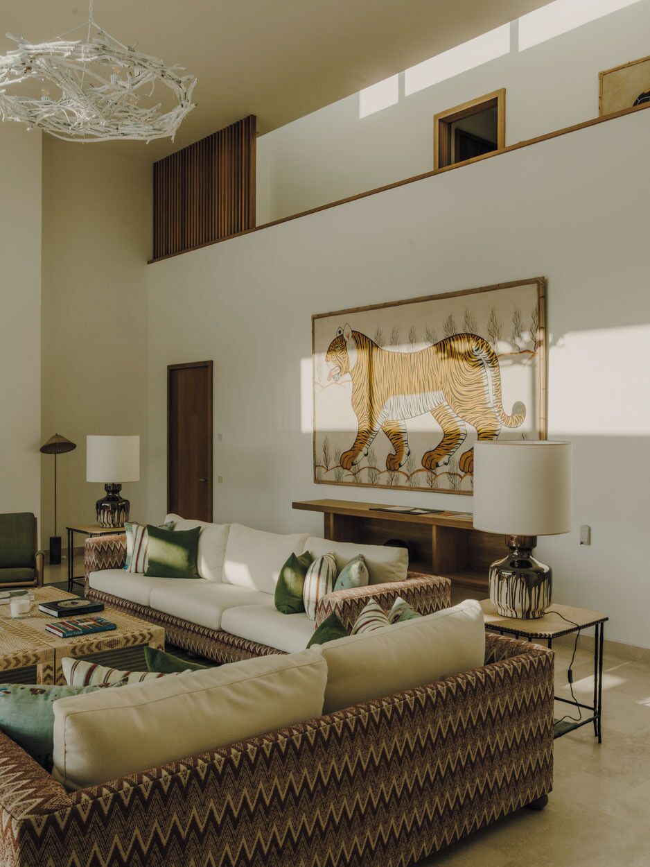 A spacious living room with a high ceiling, a large wall-mounted tiger painting, a sofa set, a coffee table, and a floor lamp.