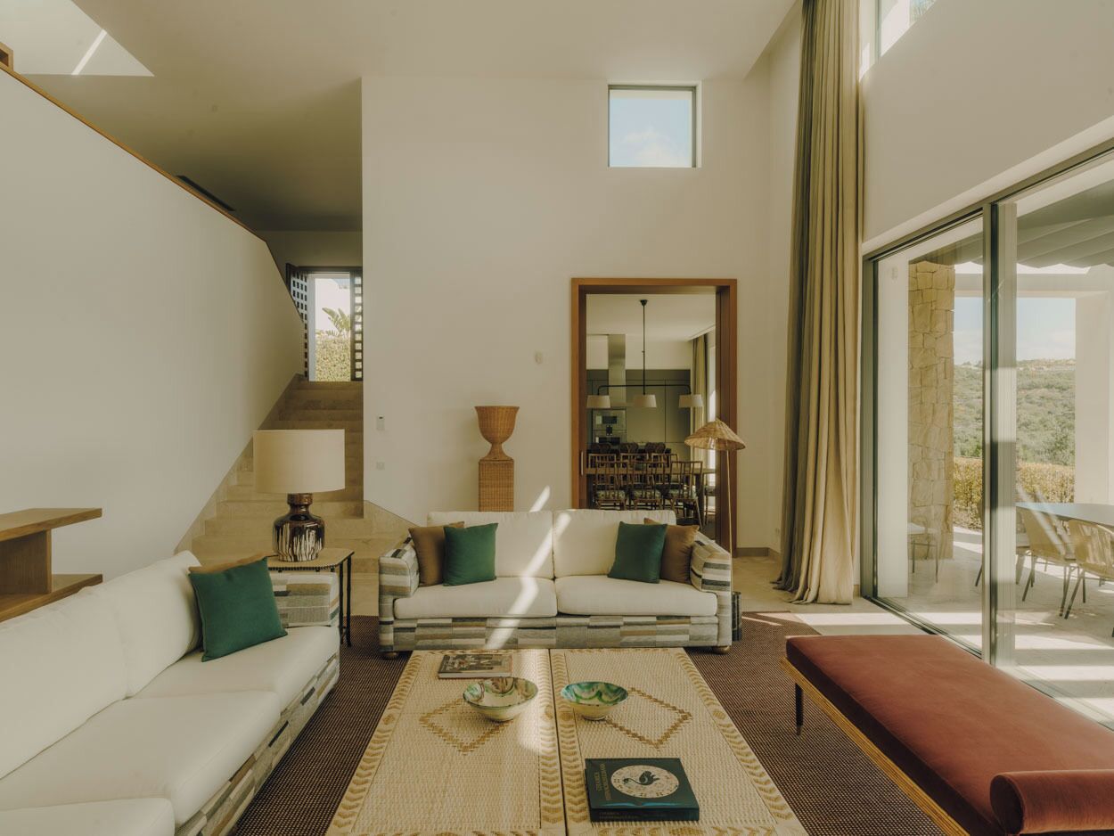 A modern living room with a sofa, coffee table, and a dining area with a glass door.
