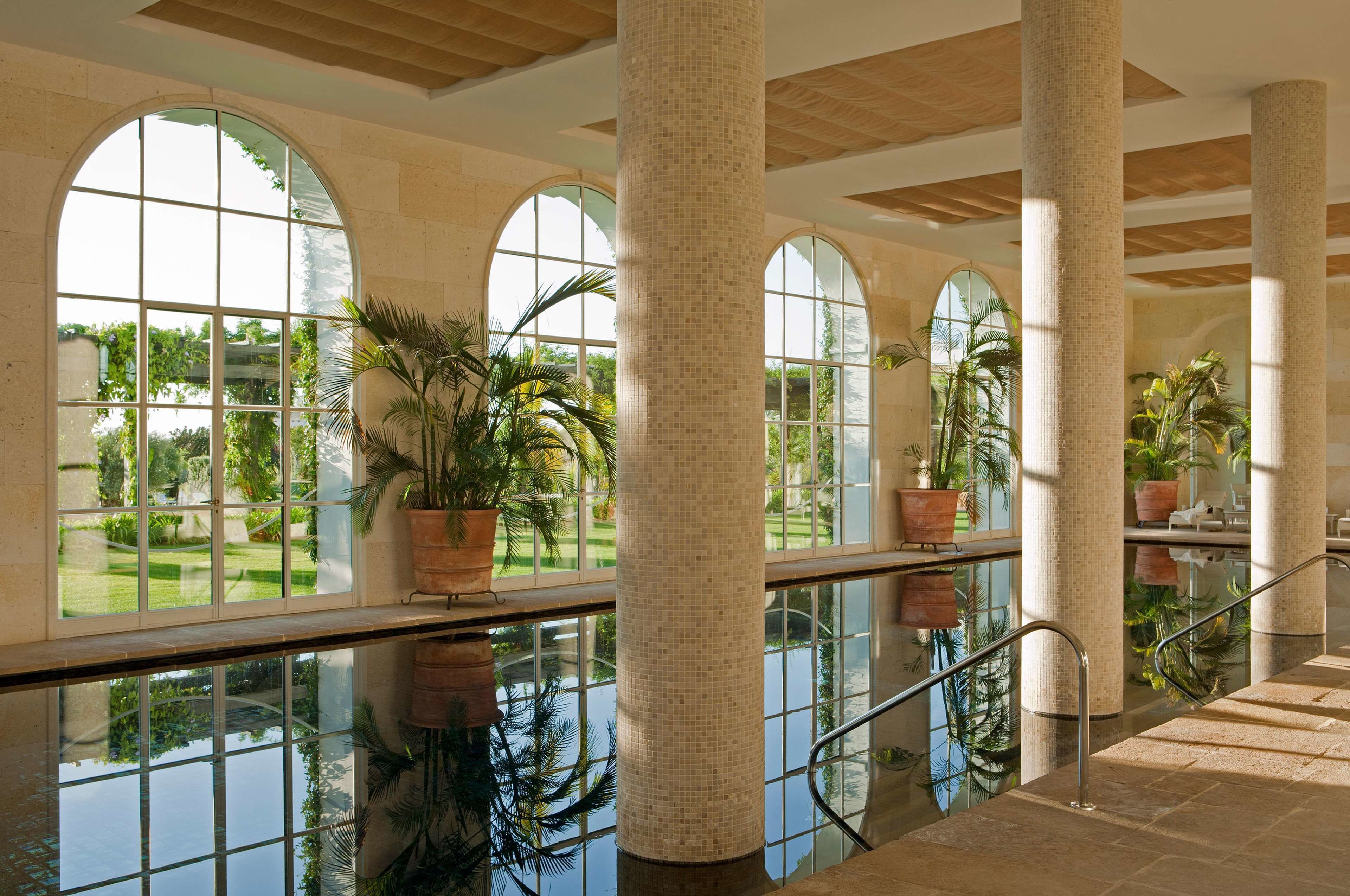 A spacious indoor area with large arched windows, tiled columns, and a reflective floor.