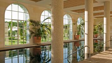 A spacious indoor area with large arched windows, tiled columns, and a reflective floor.