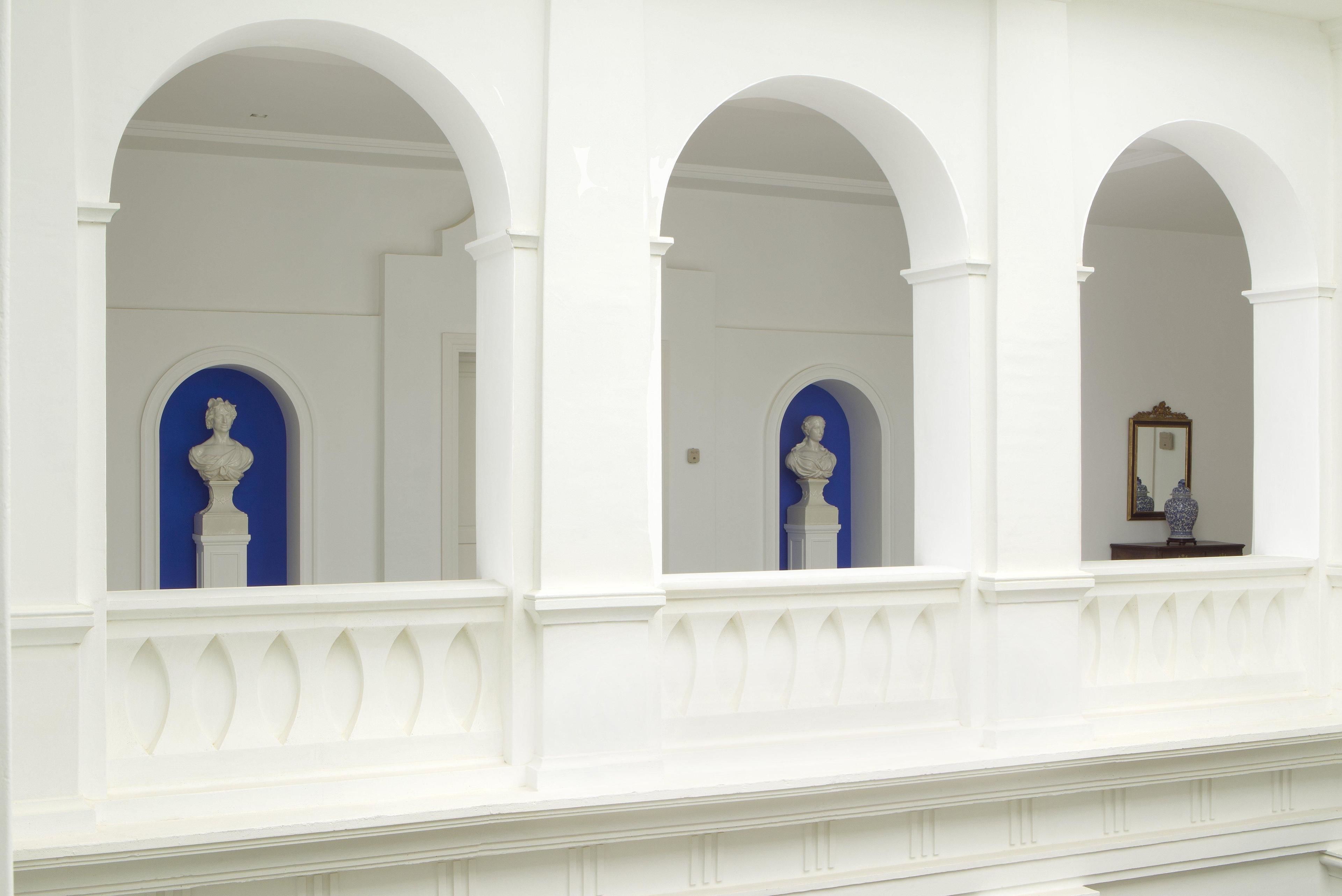 Fachada de edificio con columnas blancas y ventanas con marcos azules.