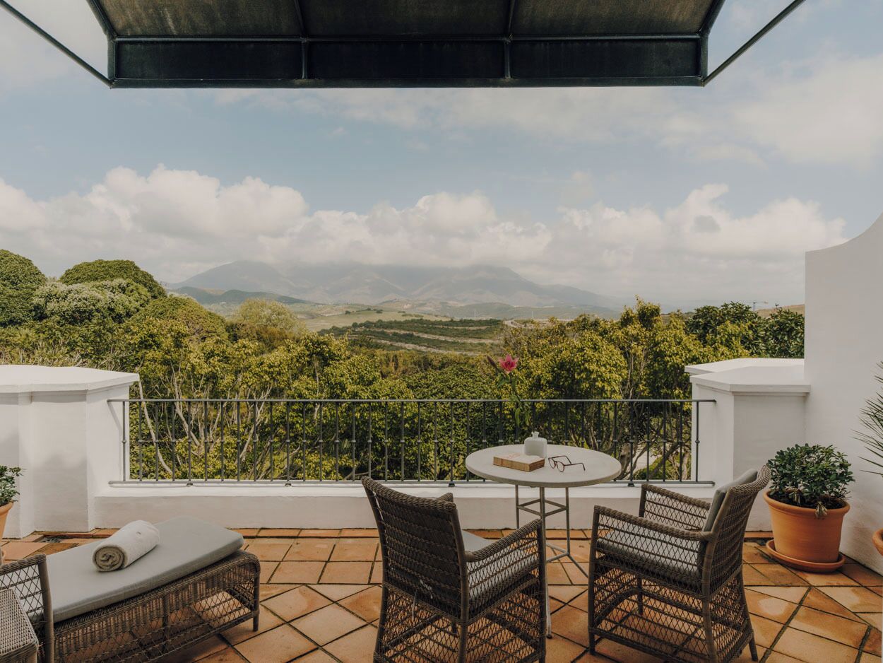 A terrace with wicker furniture, a table, and potted plants.
