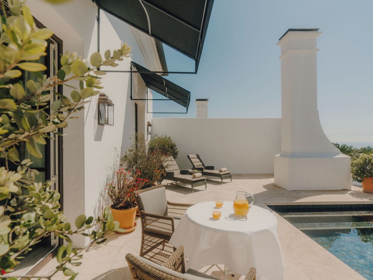 A rooftop terrace with a pool, outdoor seating, and potted plants.