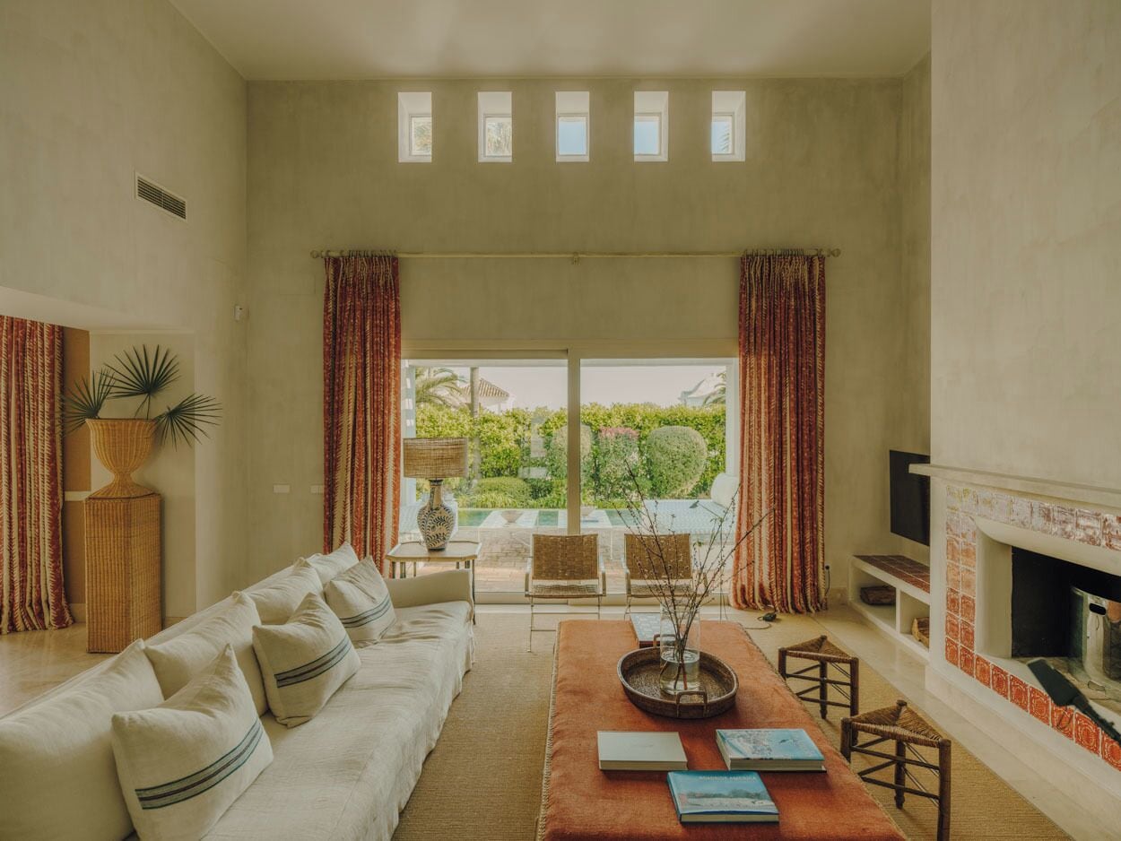 Un salón con sofá, sillas, chimenea y vista a espacios verdes.