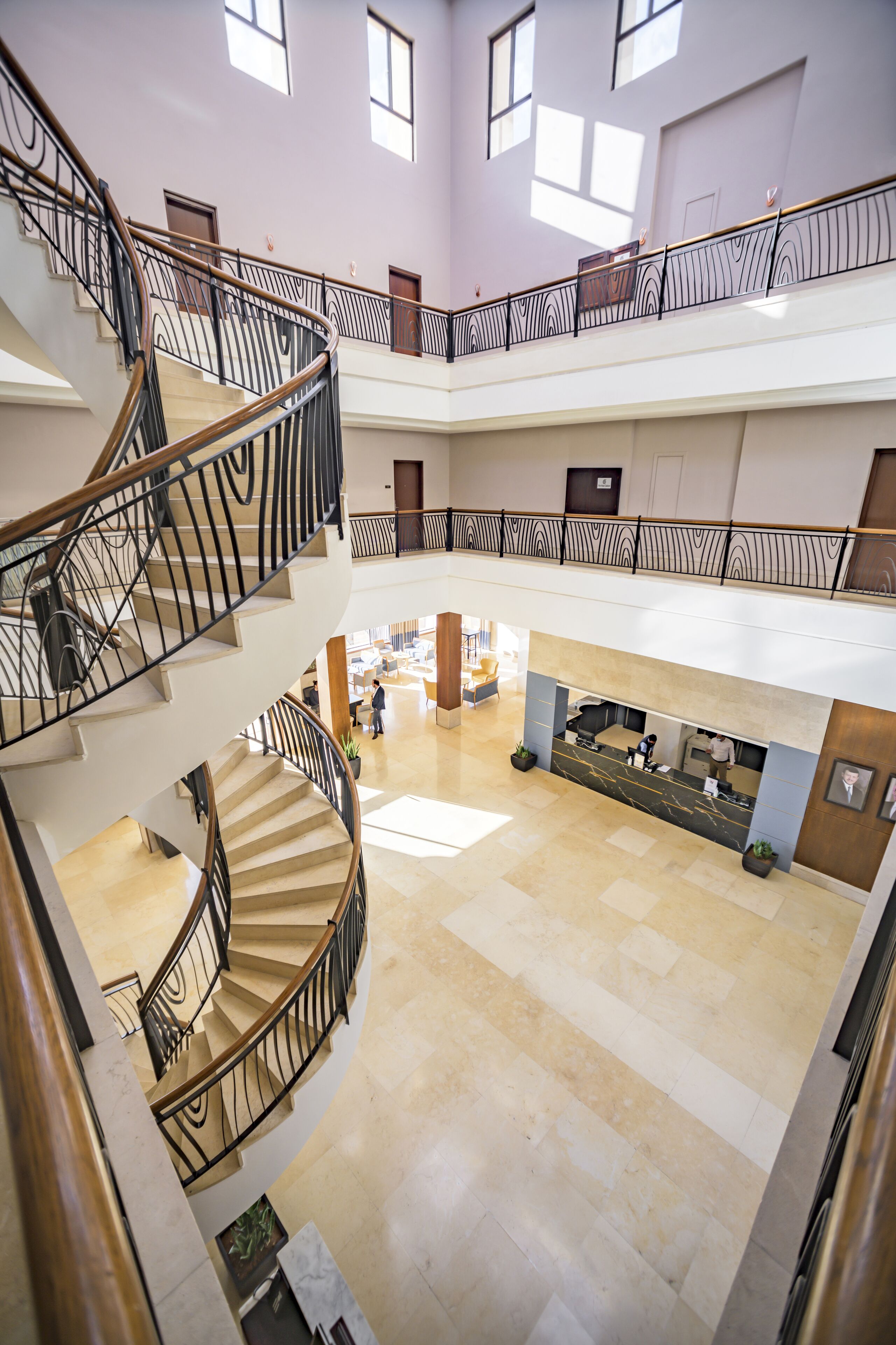 Un intérieur à plusieurs niveaux comprenant un espace central ouvert, un escalier et un espace d’accueil.