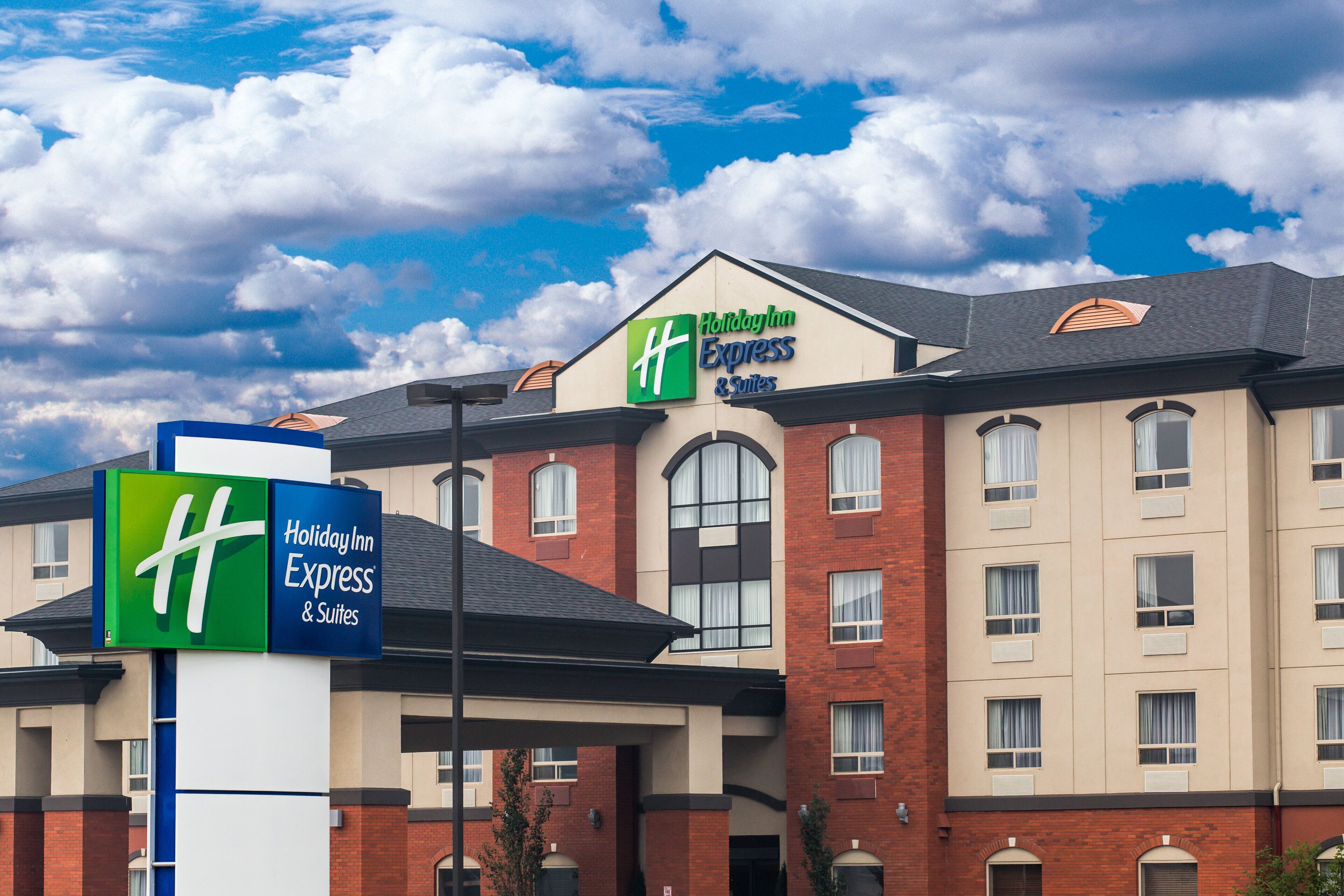 Et Holiday Inn Express & Suites hotel med synlig skiltning, murstensfacade og mange vinduer.