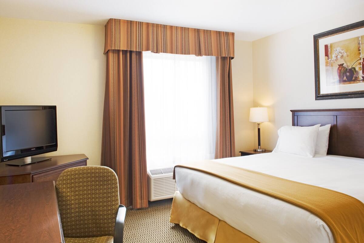 A hotel room with a bed, a television, a desk, and a chair.