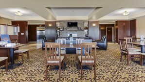 A spacious hotel lobby with a patterned carpet, wooden furniture, and a central seating area with a fireplace. - Holiday Inn Express & Suites Slave Lake by IHG (Slave Lake)