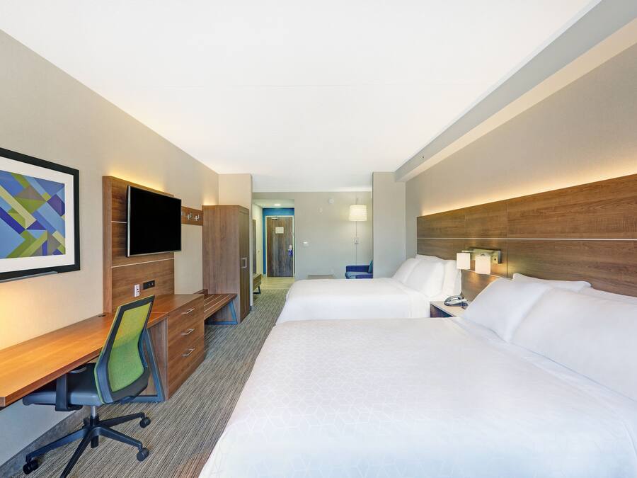 Une chambre d’hôtel avec deux lits, un bureau, une chaise, une télévision et une lampe.