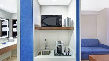 A compact kitchenette with a microwave, coffee maker, and sink.