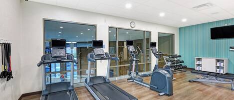 A gym with treadmills, elliptical machines, and a weight bench.