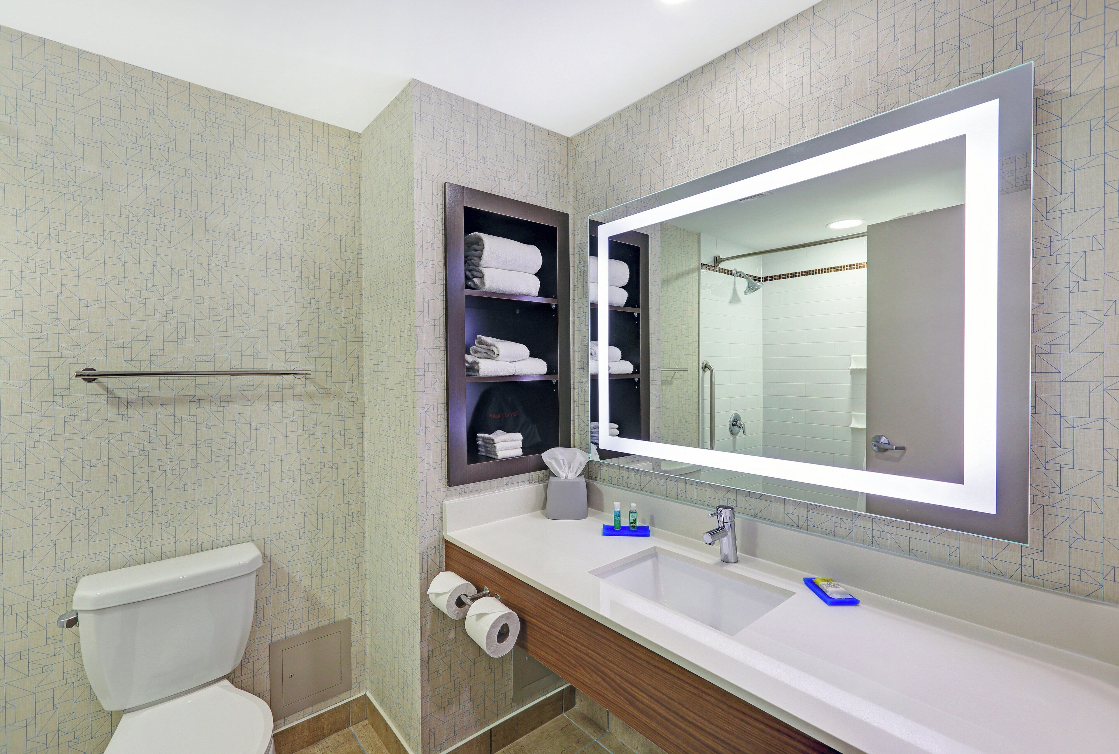 A modern bathroom with a toilet, a sink, a mirror, and a towel rack.