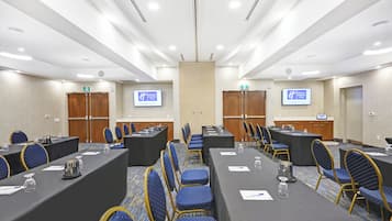 Une salle de conférence dotée de plusieurs tables et chaises, ainsi que de plaques nominatives et de verres à eau.