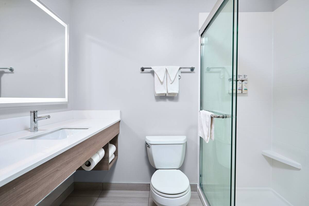 A modern bathroom with a white sink, toilet, and glass shower enclosure.