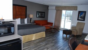 Habitación de hotel con cama, sofá, mesa de comedor, microondas y refrigerador.
