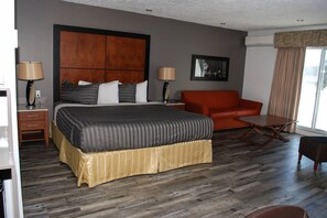 A hotel room with a large bed, a sofa, a coffee table, and a TV.