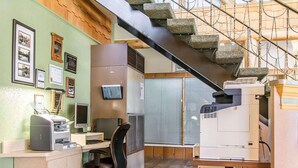 Una oficina en casa con escritorio, computadora, impresora y una escalera.
