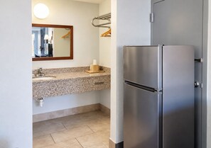 Eine moderne Küche mit einem Edelstahl-Kühlschrank, einer Granitarbeitsplatte und einem Spiegel über dem Waschbecken.