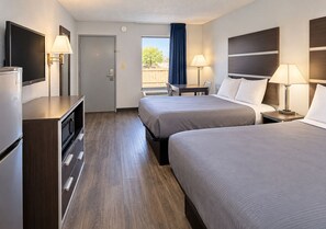 A hotel room with two beds, a desk, a TV, and a window with a view. - Newnan Nook (Newnan)