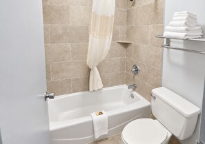 A bathroom with a bathtub, toilet, and towel rack. - Newnan Nook (Newnan)