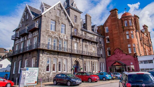 A historic building with the sign "COLUMBA HOTEL" on the facade, featuring classic architectural elements and a parking area in front. - Columba Hotel (Oban)