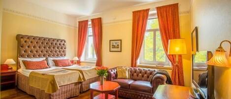 Une chambre d’hôtel avec deux lits, un canapé, une petite table et un bureau avec une lampe.