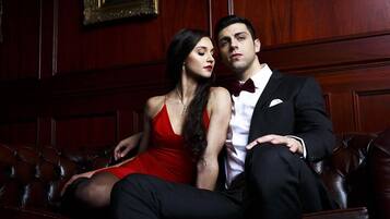 A man and woman sitting on a leather couch in a room with wooden paneling and framed artwork on the walls.