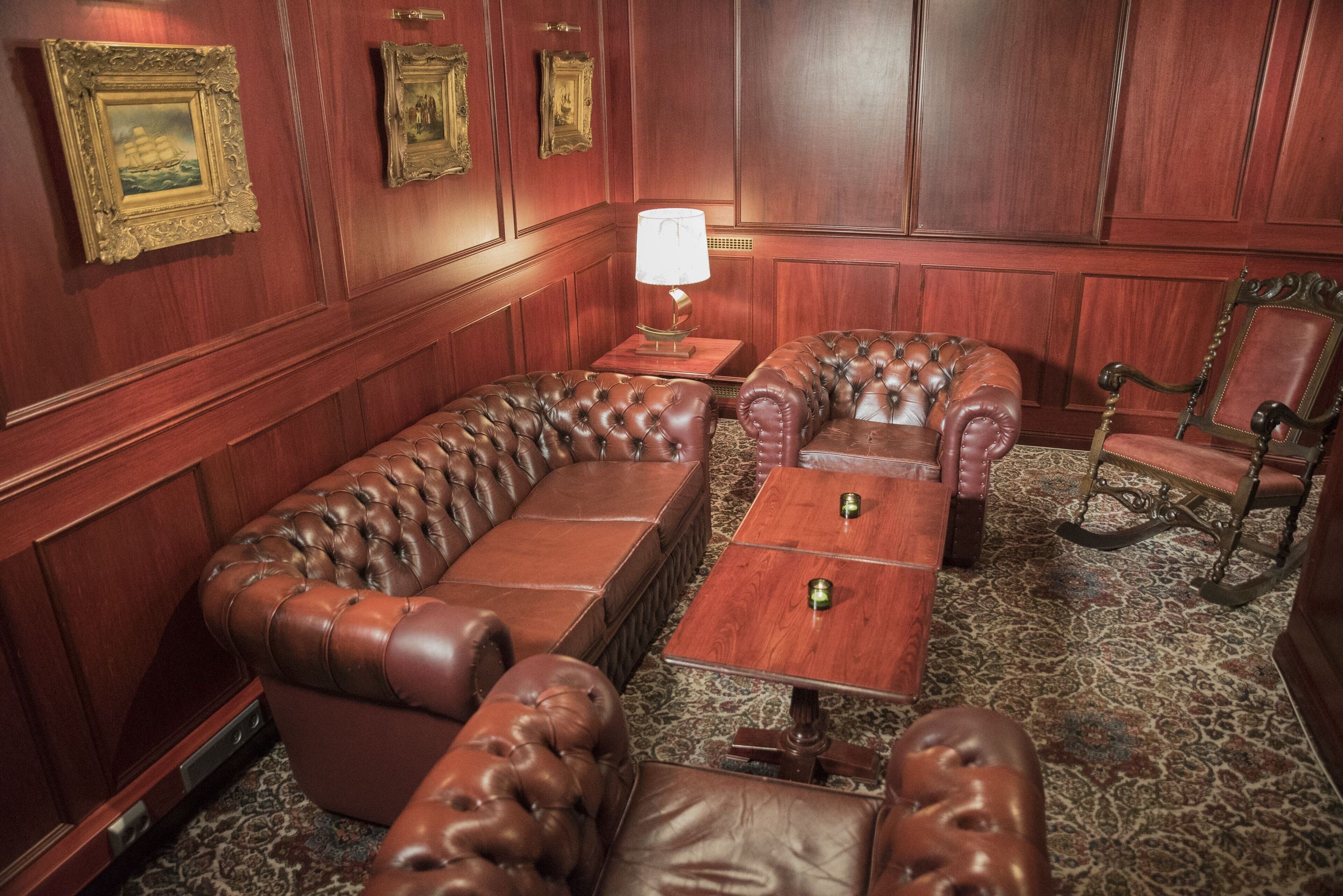 A room with a leather sofa, a wooden coffee table, and a patterned carpet.