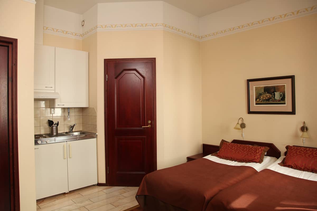 A bedroom with a wooden door, a bed with two pillows, a nightstand, and a framed picture on the wall.