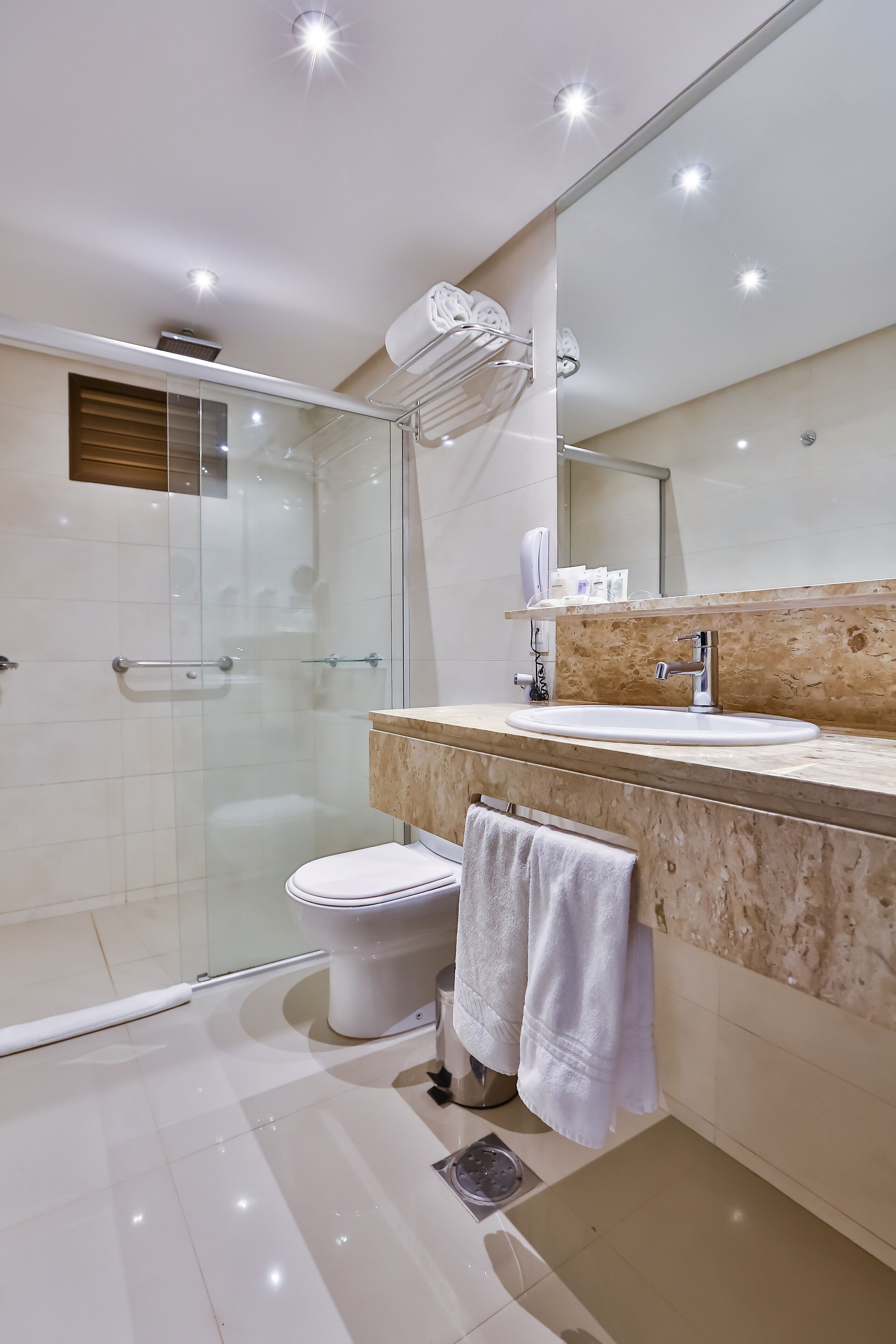 Un baño moderno con cabina de ducha de vidrio, inodoro blanco y lavabo con encimera de mármol.