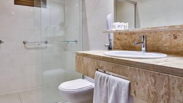 Un baño moderno con cabina de ducha de vidrio, inodoro blanco y lavabo con encimera de mármol.