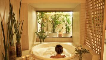 Un baño con bañera, plantas en macetas y una ventana.