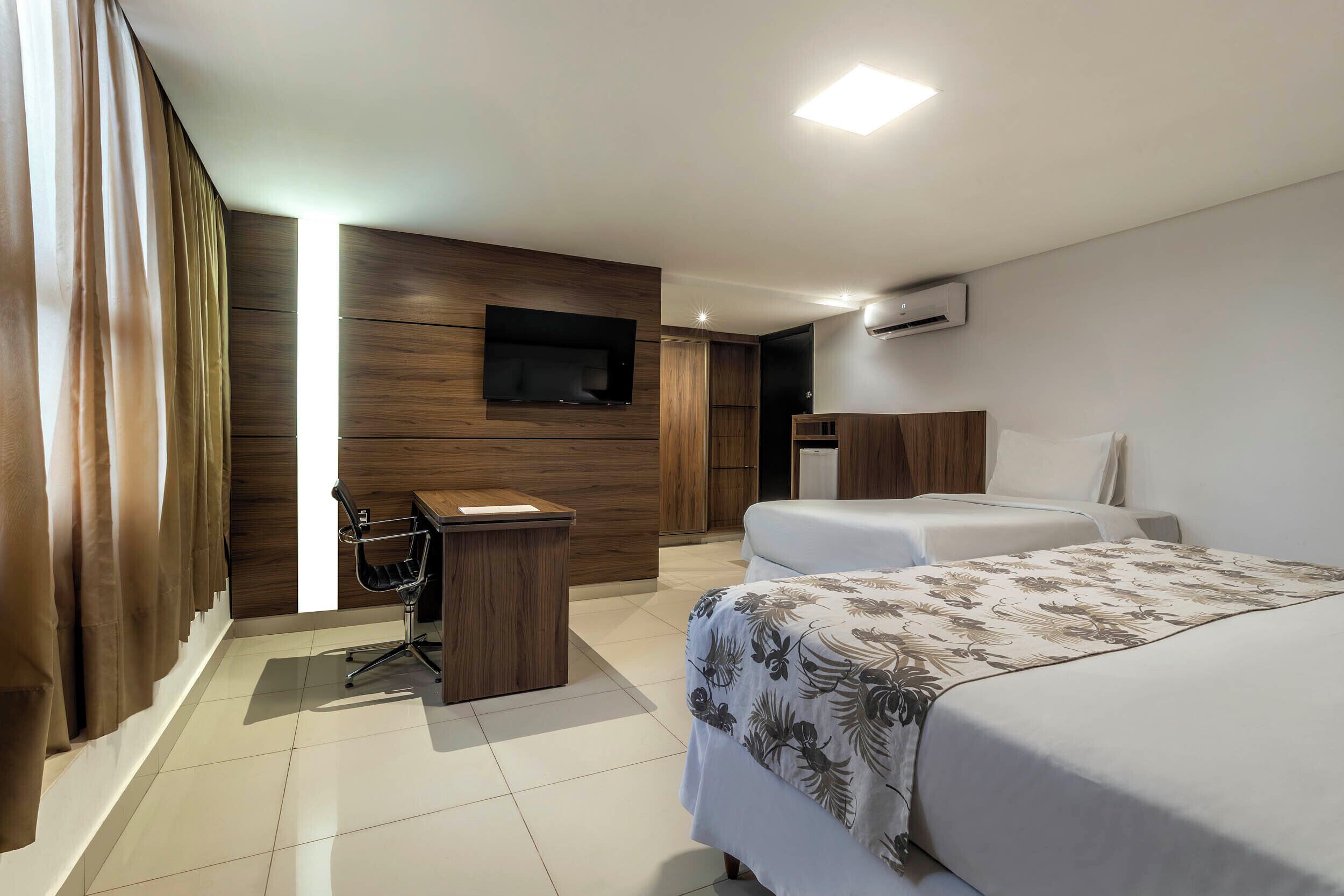 Une chambre d’hôtel équipée d’un lit, d’un bureau, d’une chaise, d’une télévision et d’un appareil de climatisation.