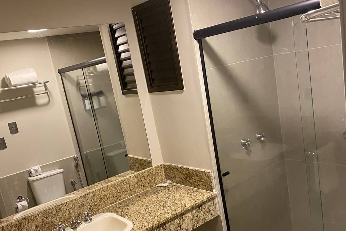 A modern bathroom with a granite countertop sink, a glass shower enclosure, and a toilet.