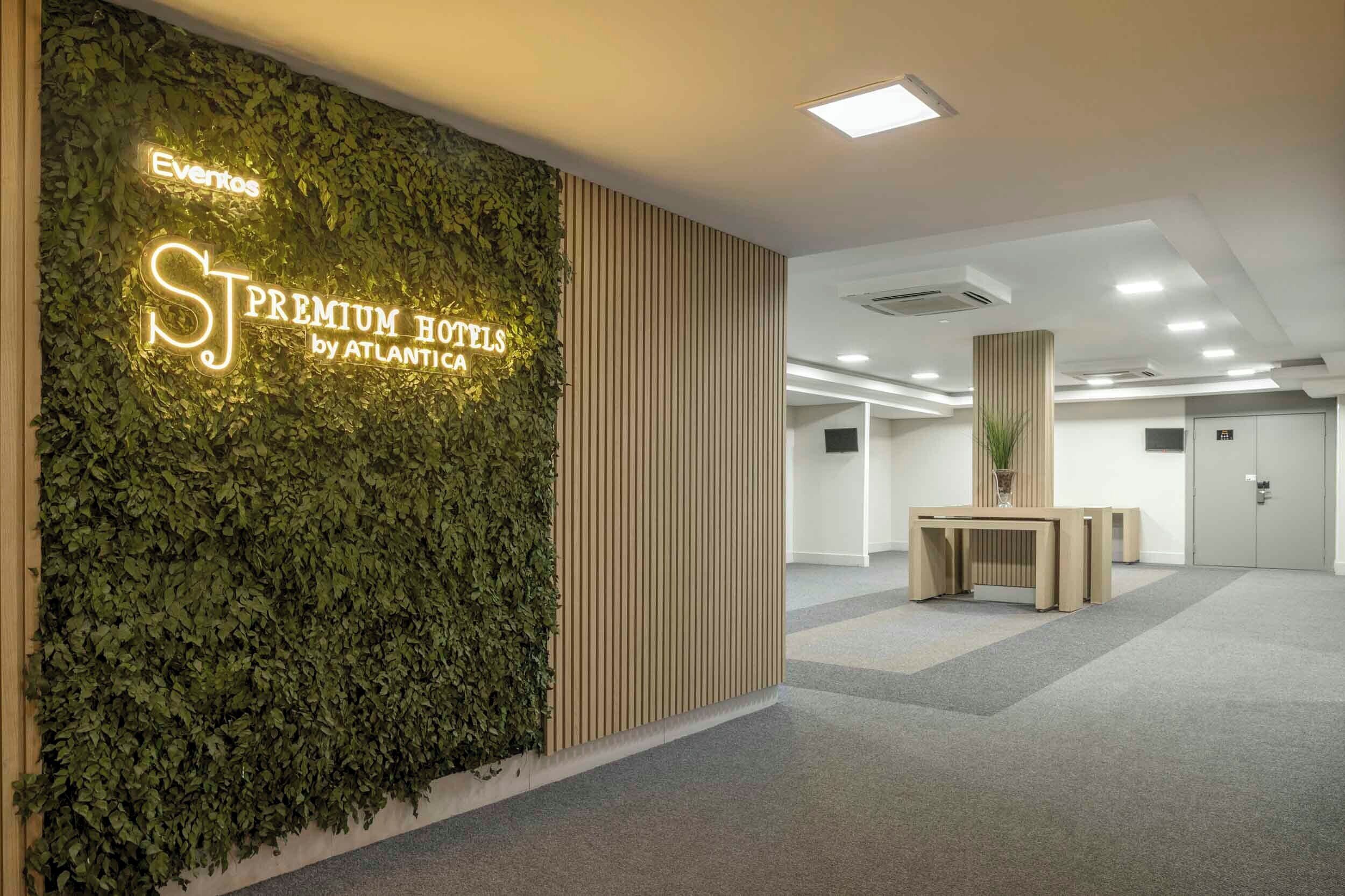 A modern hotel lobby with a vertical garden, a reception desk, and a sign for 'ST PREMIUM HOTELS by ATLANTICA.'