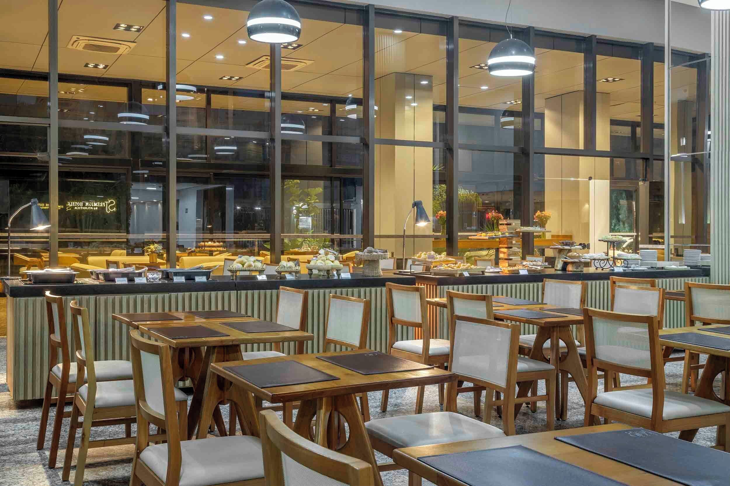A restaurant with a buffet, wooden tables, and chairs.