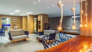 A modern living room with a sofa, chairs, and a wooden coffee table. - Hotel Costamar Ponta Verde (Maceió)