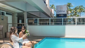 A poolside area with a clear blue pool, a sign for Hotel Costamar, and a view of palm trees. - Hotel Costamar Ponta Verde (Maceió)