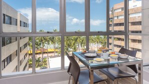 A dining area with a glass table and chairs, overlooking a beach and palm trees. - Hotel Costamar Ponta Verde (Maceió)